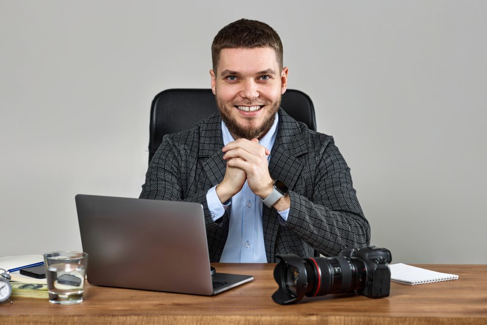 bearded male photographer smiling while working at her desk. bearded male photographer smiling while working at her desk.